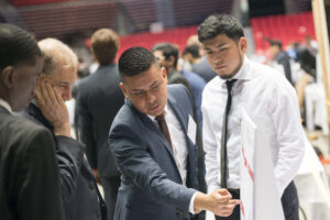 3 Senior engineering students showcase their project to a faculty member.